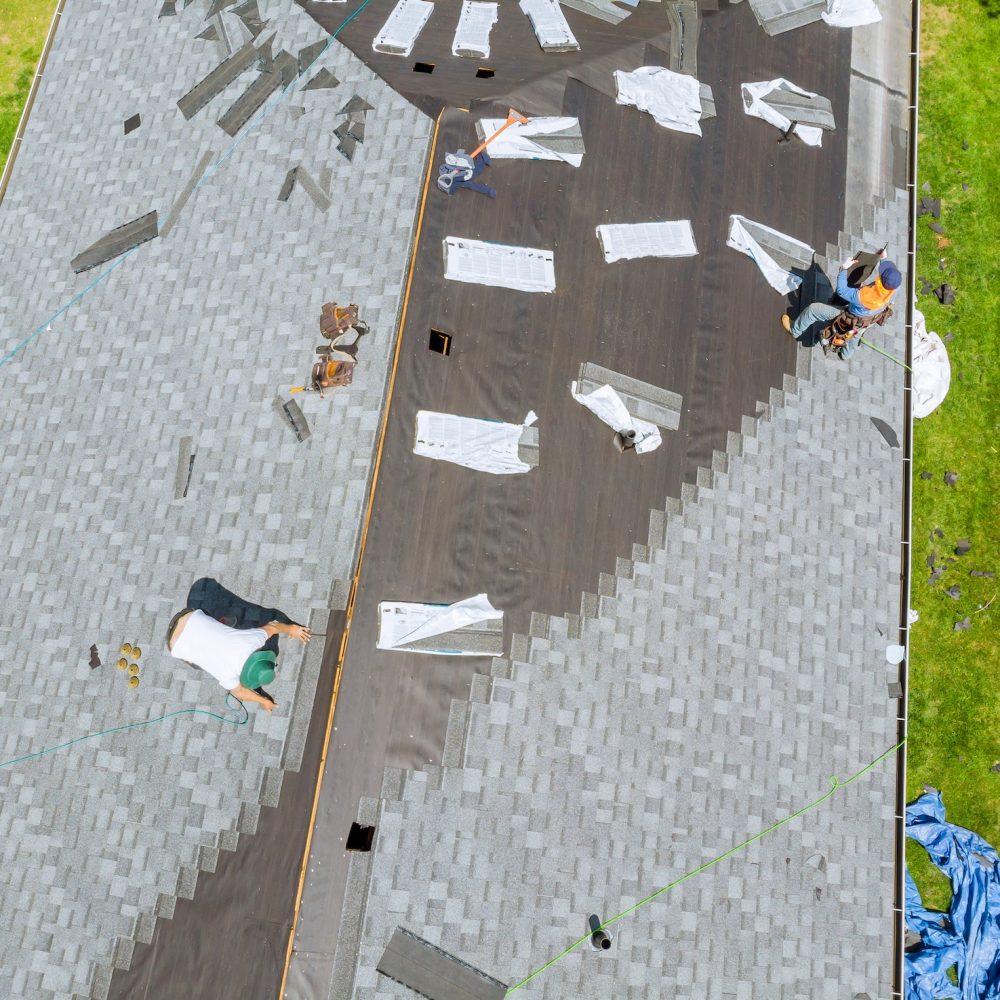 Roofer working on replacement asphalt shingle roof construction